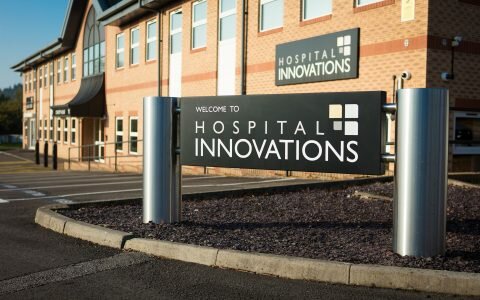 A black welcome sign with white writing and the Hospital Innovations logo stands outside their Talbot Green headquarters