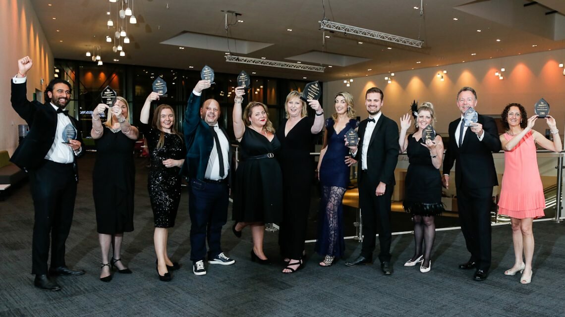 Winners of the Wales Business Awards cheering and holding their awards in the air.