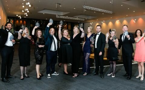 Winners of the Wales Business Awards cheering and holding their awards in the air.