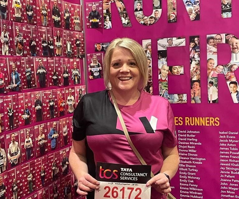 Catherine Robinson smiles as she prepares to run the London Marathon. She has short blonde hair and is wearing a black and purple t-shirt.
